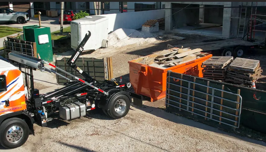 Sabatello roll-off truck placing a 16-yard dumpster on a tight job site